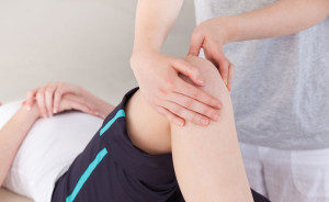 Masseuse massing the knee of a sportswoman